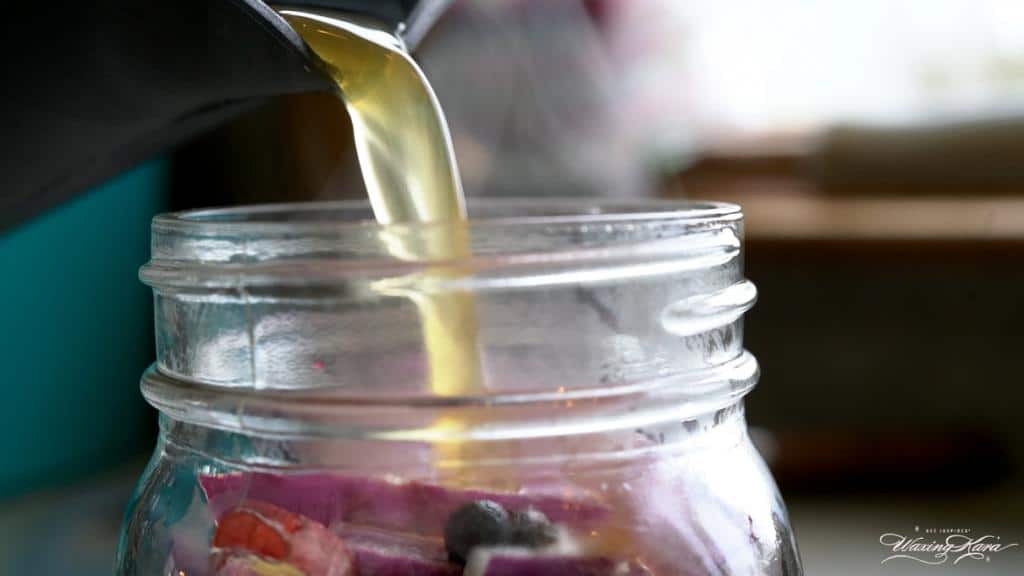 Pouring pickling juice over sliced onion in ball jar