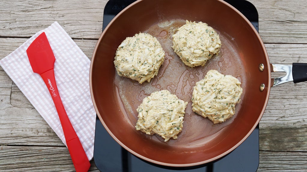 maryland crab cakes prepared and uncooked in frying pan on wood table