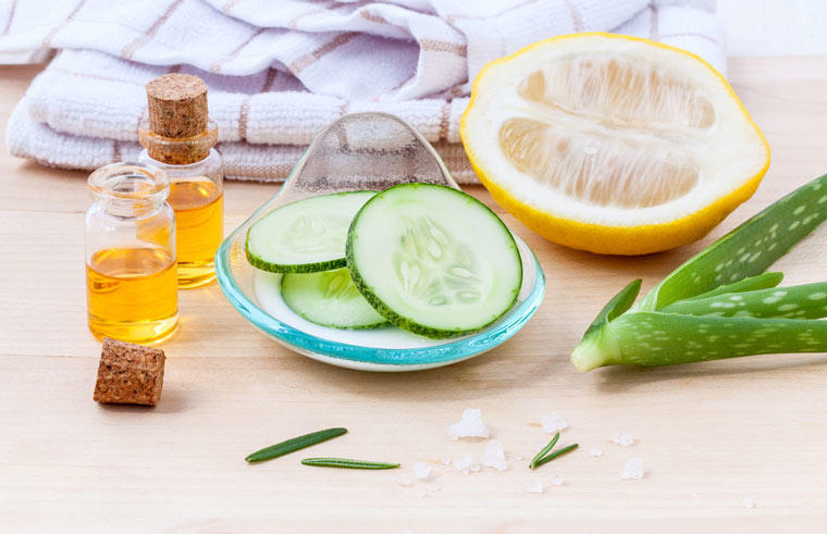 raw ingredients for cucumber eye treatment on counter. Ale plant, sliced cucumber, lemon, honey towel and more
