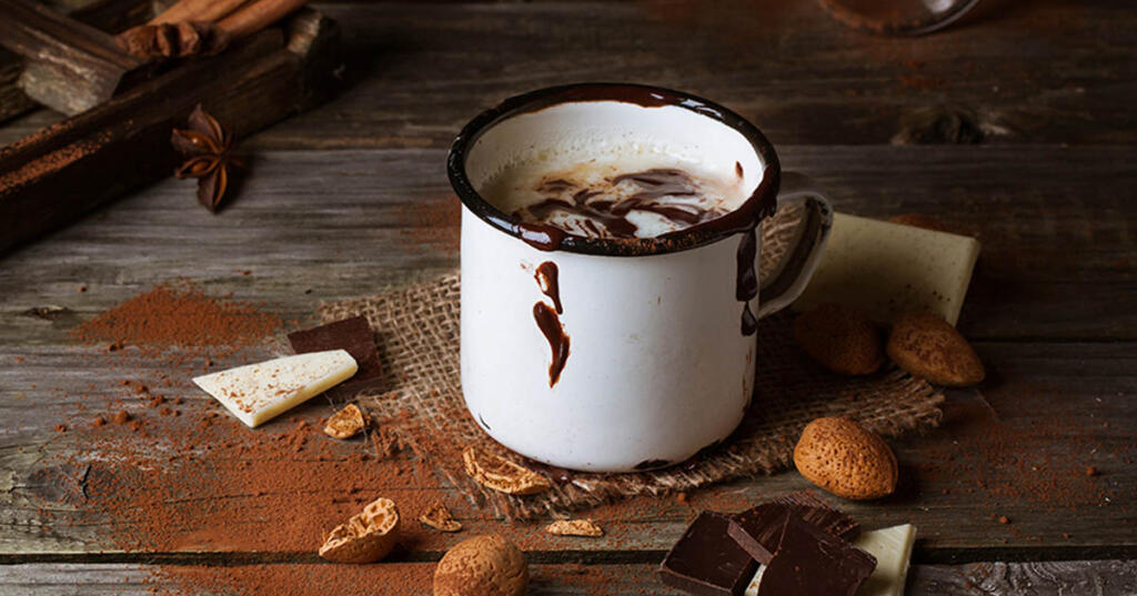 Dairy-Free Hot Cocoa on wood table surrounded by ingredients