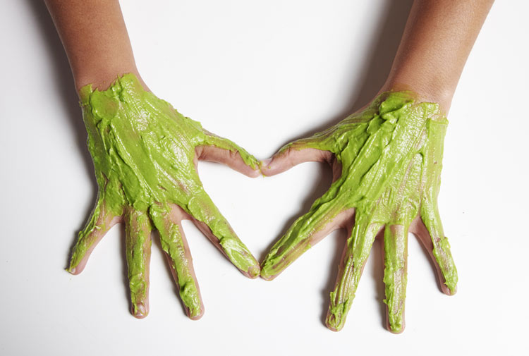 hands with avocado cuticle treatment containing honey and avocado palm side down on white table