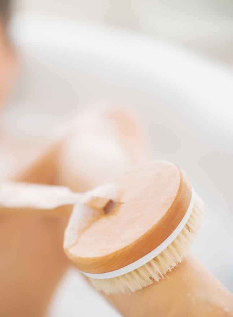 A dry brush being used on the legs in a bath tub