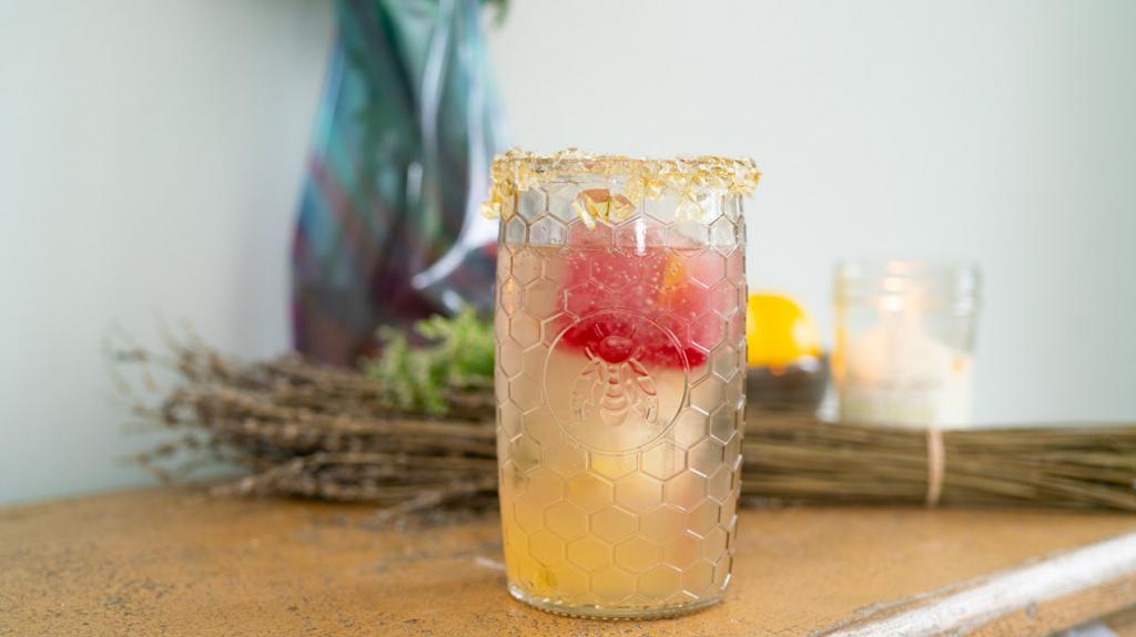 Lemon Vodka Cocktail with honey lollipop rim on counter close-up