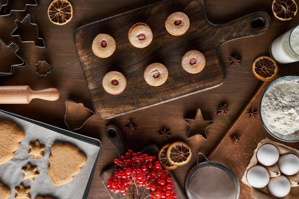 holiday cookies on wood counter with dried oranges and cookie cutters with raw ingredients