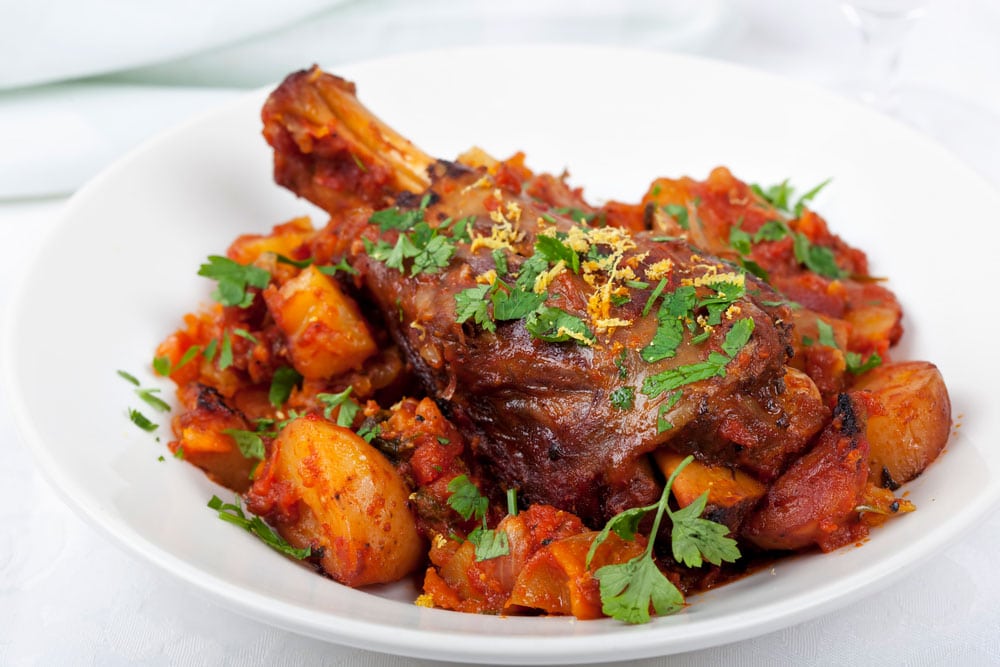 lamb shank on plate with carrots on a white plate