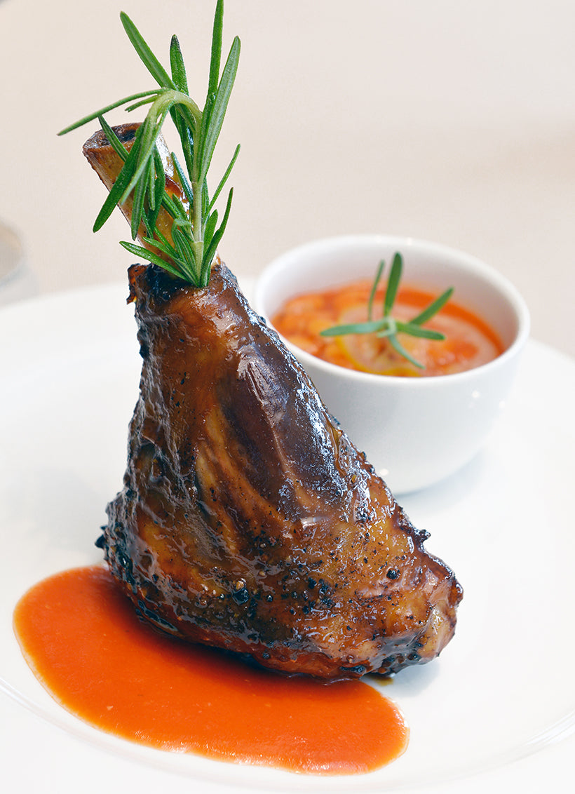 lamb shank with sauce on white plate with tomato sauce