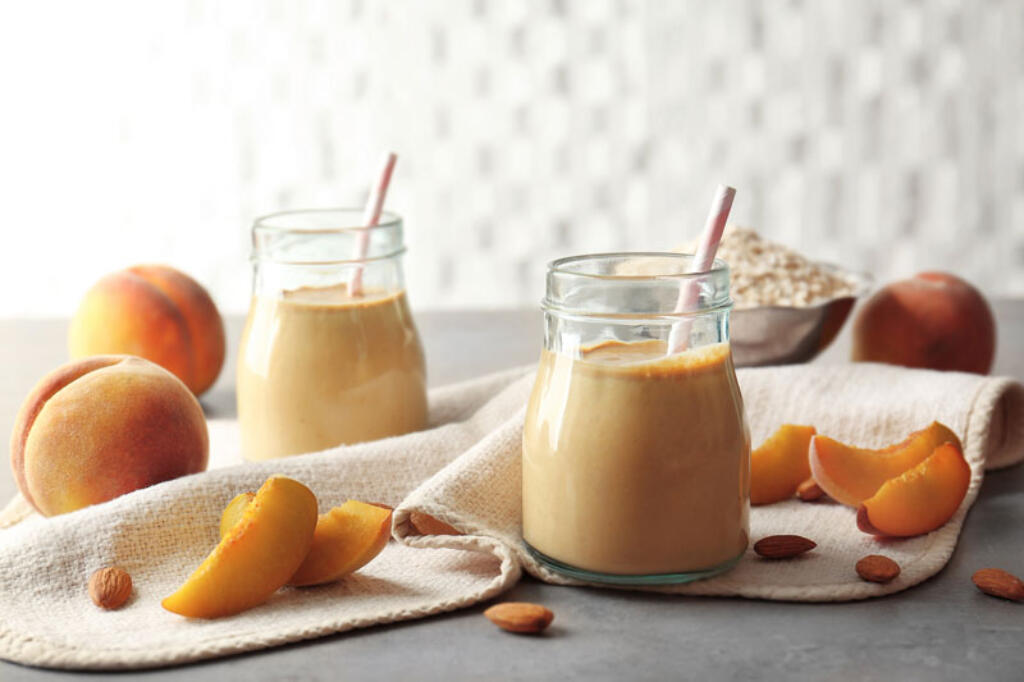 Peach Smoothie with fresh peaches and raw oats in glass jars with straws