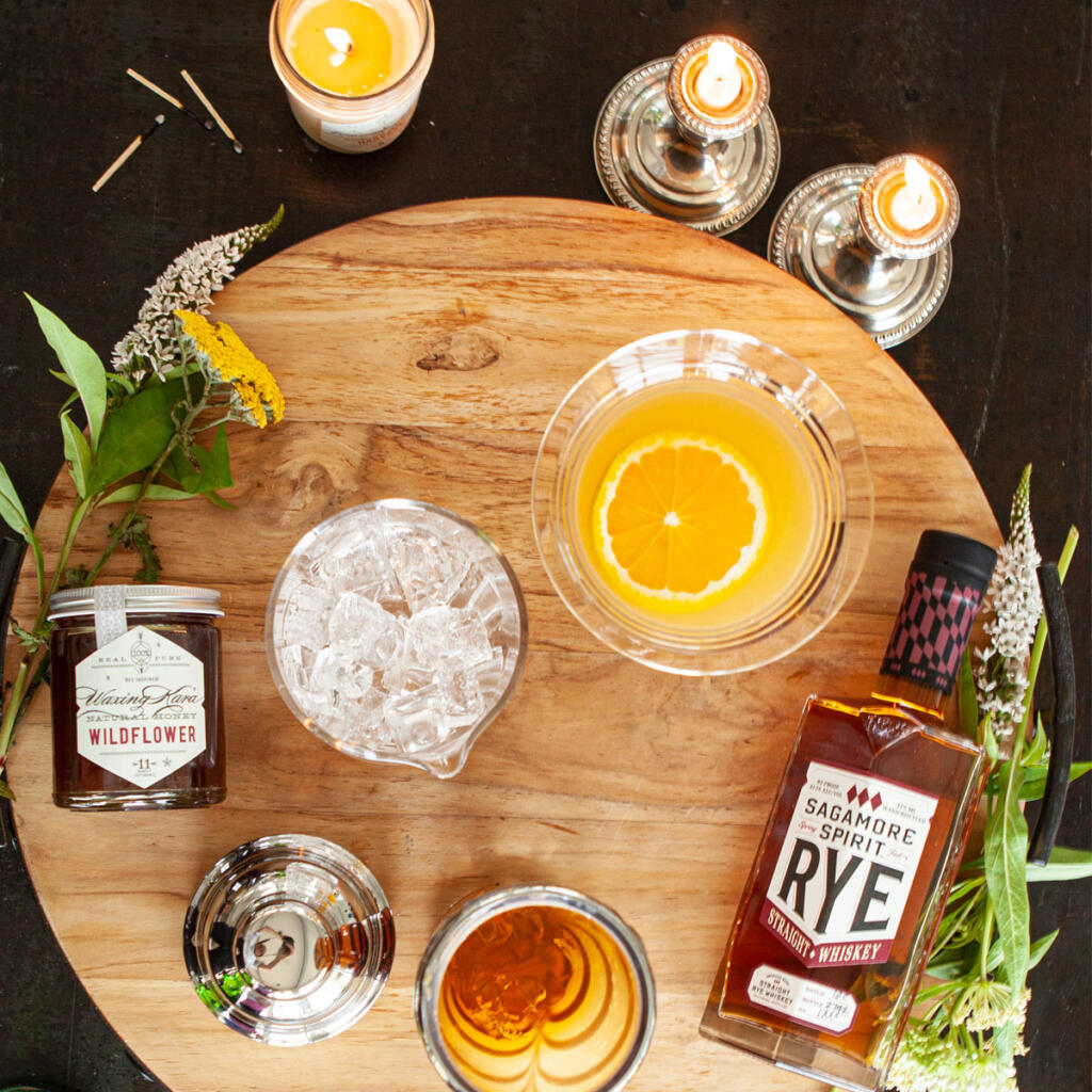 Rye Crush set with Sagamore Rye, fresh squeezed orange juice our honey and candles on wood cutting board