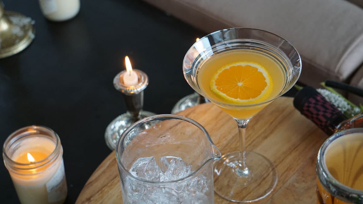 closeup of rye crush in martini glass and lit candle on wood board with ice