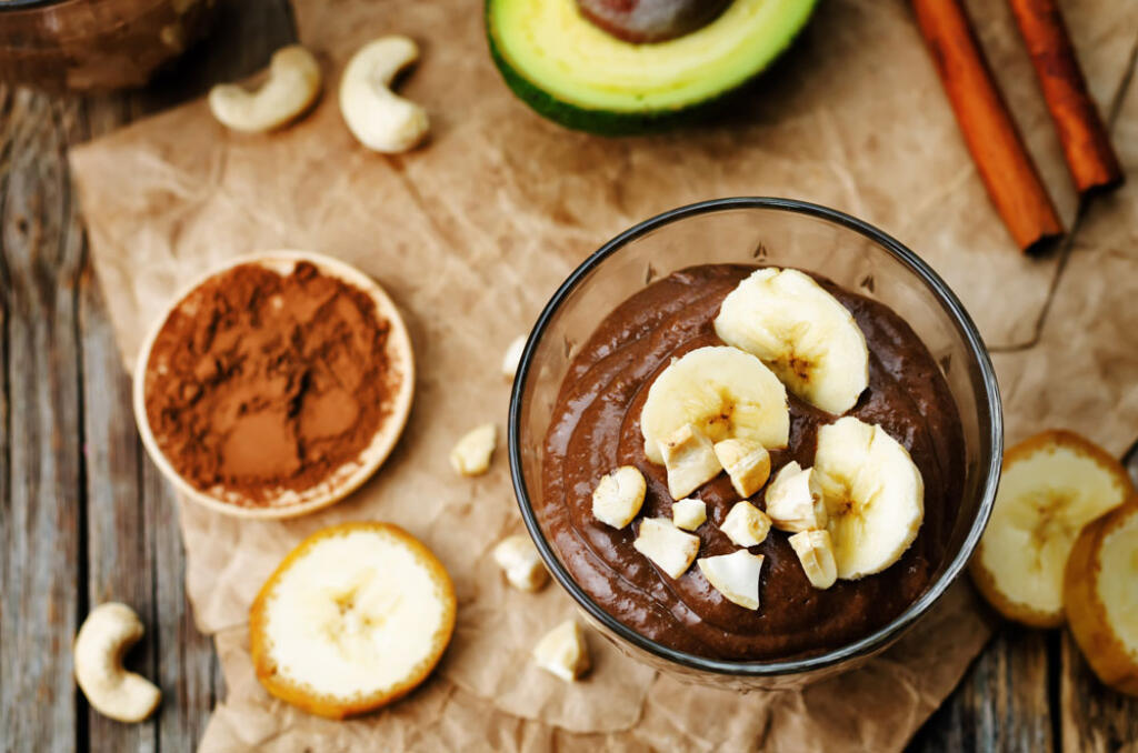 raw chocolate pudding in a glass bowl topped with bananas and nuts