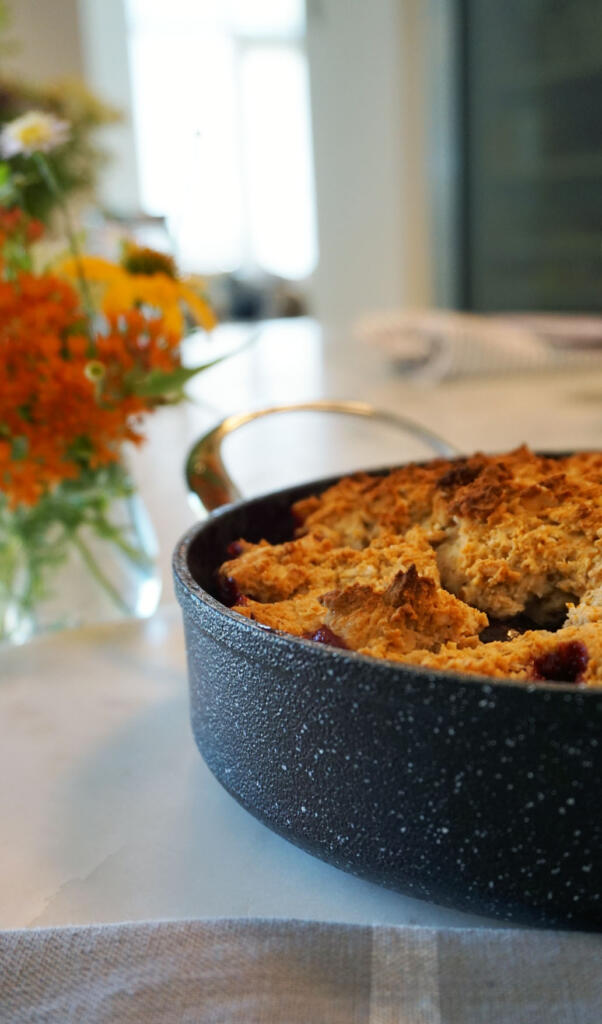 fresh-baked cherry cobbler on kitchen counter with flowers in background