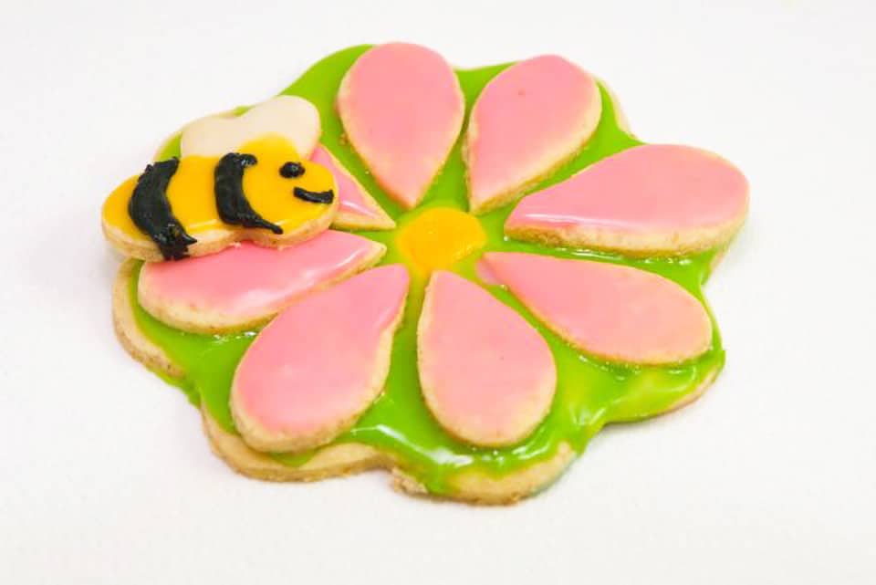 Vegan sugar cookie decorated as a flower with a bumble bee on top