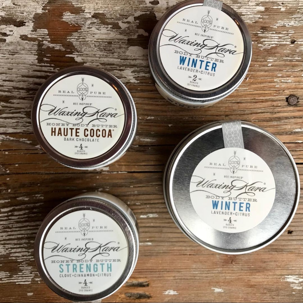 overhead shot of a tub of Strength body butter, a tub of Haute Cocoa body butter, and two tubs of Vegan Winter body butter