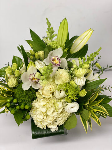 Classic white arrangement including a Roses Cymbidium orchids snowballs and Lisianthus