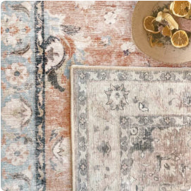 Close-up of two overlapping patterned rugs beside a bowl of dried citrus.