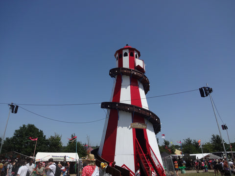 A white and red helter-skelter with a brown slide, surrounded by festival goers, taken at Glastonbury 2019