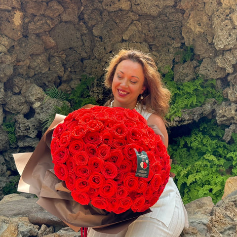 a A joyful recipient admires the Elegant 100 Ferrari Red Roses Bouquet from Floral Atelier Australia, expertly arranged and beautifully wrapped, symbolizing a grand gesture of love, available for same day delivery by a leading florist in Adelaide