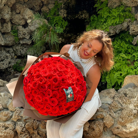 A joyful recipient admires the Elegant 100 Ferrari Red Roses Bouquet from Floral Atelier Australia, expertly arranged and beautifully wrapped, symbolizing a grand gesture of love, available for same day delivery by a leading florist in Adelaide