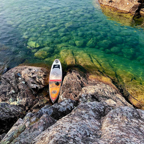 Rigid Stand Up Paddleboard resting on the rocky shore of Lake Superior