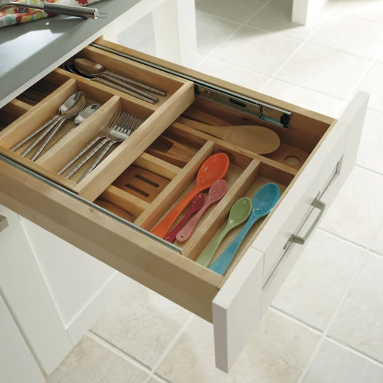 White shaker 5 piece drawer front pulled out showing a wood tiered cutlery divider with utensils