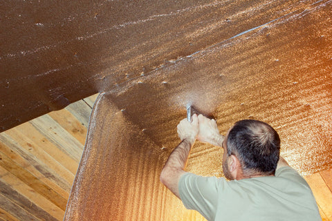 construction worker using a staple gun to staple reflective insulation to the ceiling rafters.