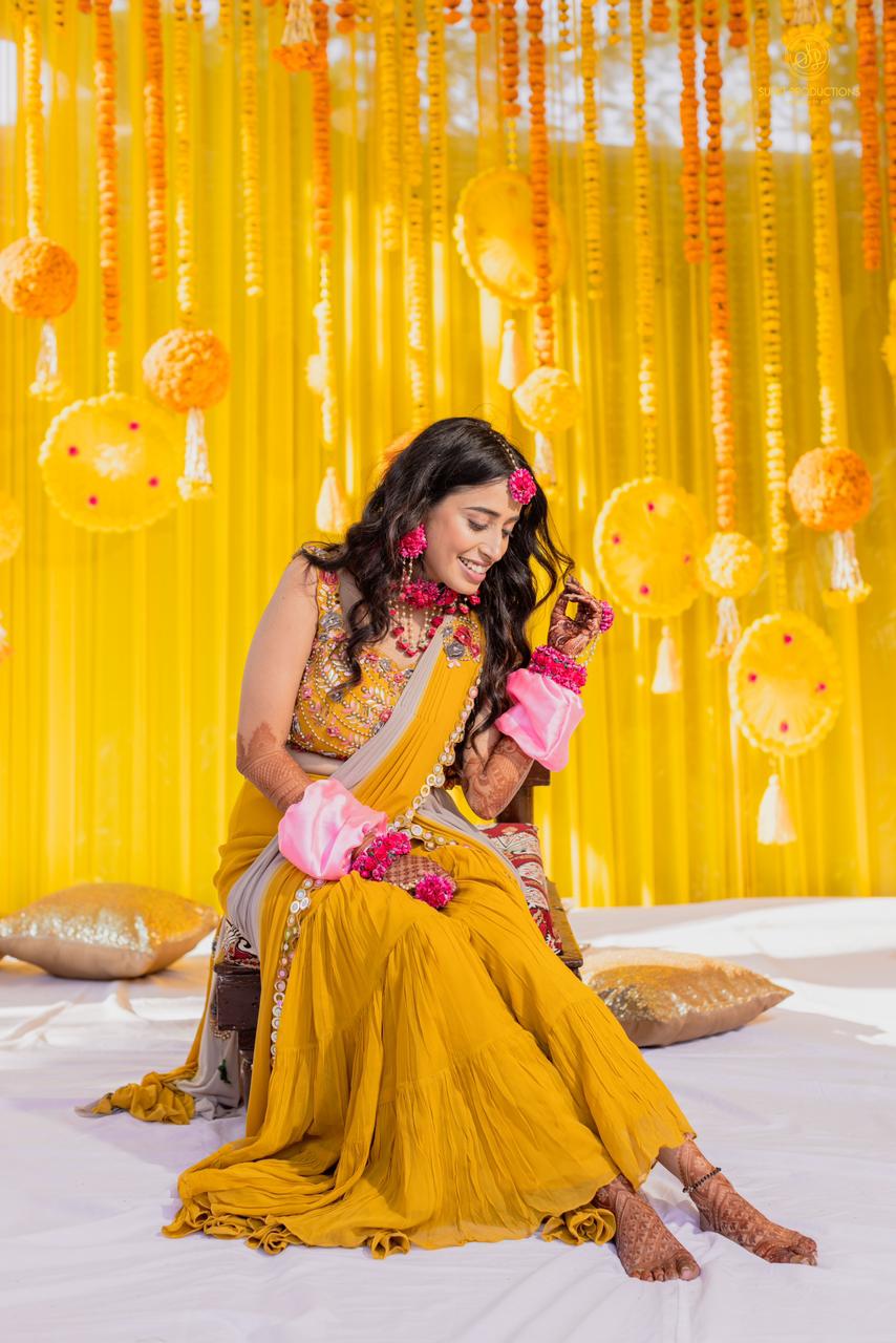 Portrait of an Indian bride sitting on stage and posing in front of camera  on haldi ceremony - SuperStock