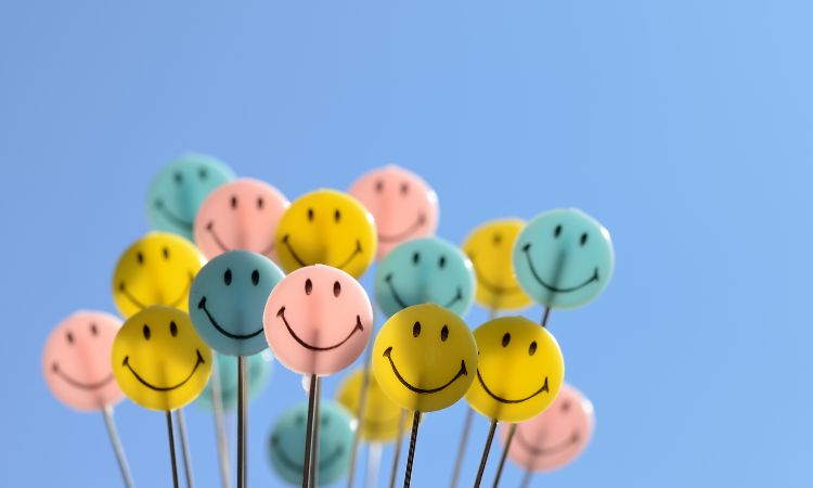 group of smiling emoji faces on wire multi coloured on blue sky background