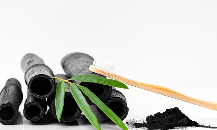 Charcoal and natural bamboo toothbrush and mint sprig arrangement for natural oral care