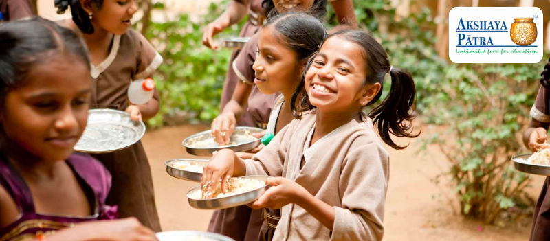 A little girl eating rice and smiling to the camera