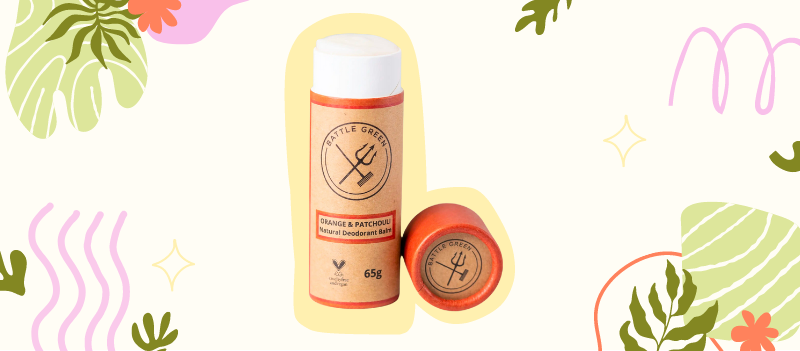 Orange & Patchouli Natural Deodorant Tube on off white background with cartoon graphics