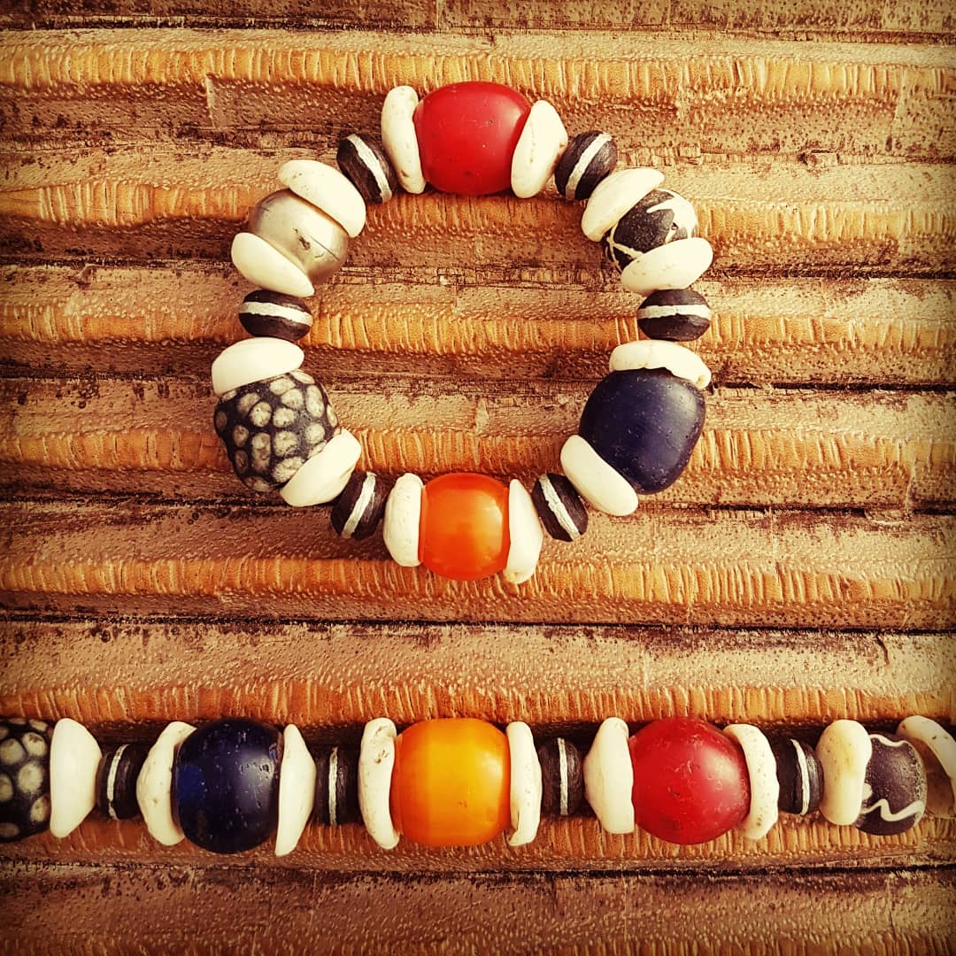 Handcrafted necklace and bracelet with white shells from Indonesia, rare honey-colored Berber amber beads, ebony beads with metal inlays from the Tuareg, old red and blue glass beads from Ethiopia and glass beads from the island of Java