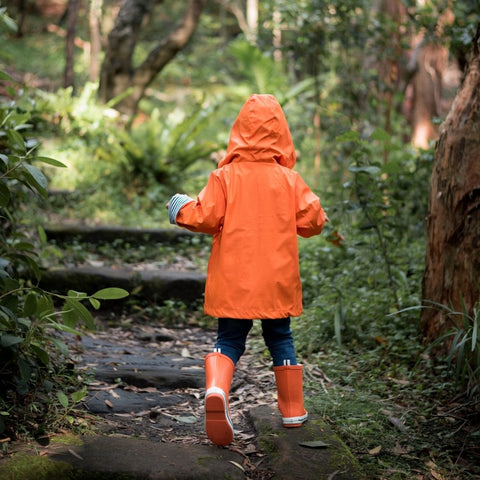 Kid wearing orange raincoat in the bush