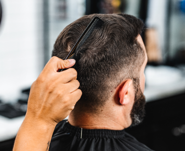 closeup of a comb parting the hair on the back of a man's head