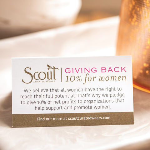 A card from Scout Curated Wears jewelry designer that reads about how the company pledges to donate ten percent of their proceeds to women's charities
