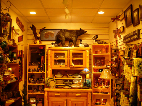 an store display of a log buffet with a bear statue and eagle painting surrounded by various beautiful giftware