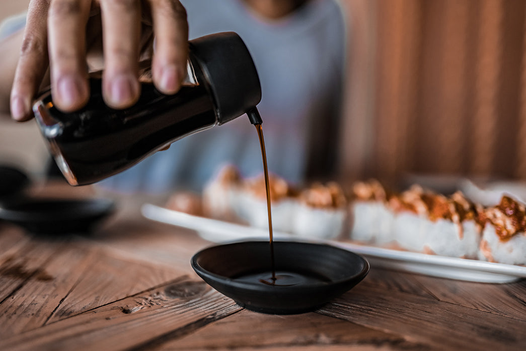 pouring soy sauce in a black saucer on bamboo mat #umami