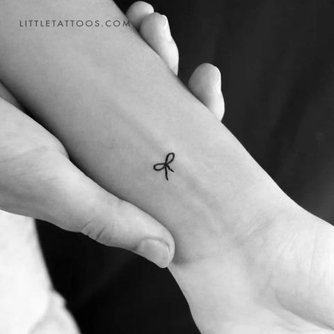 Hailey Bieber's tattoos: Fine line bow tattoo