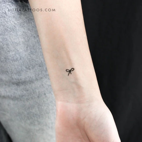 Hailey Bieber's Tattoos: fine line micro bow tattoo