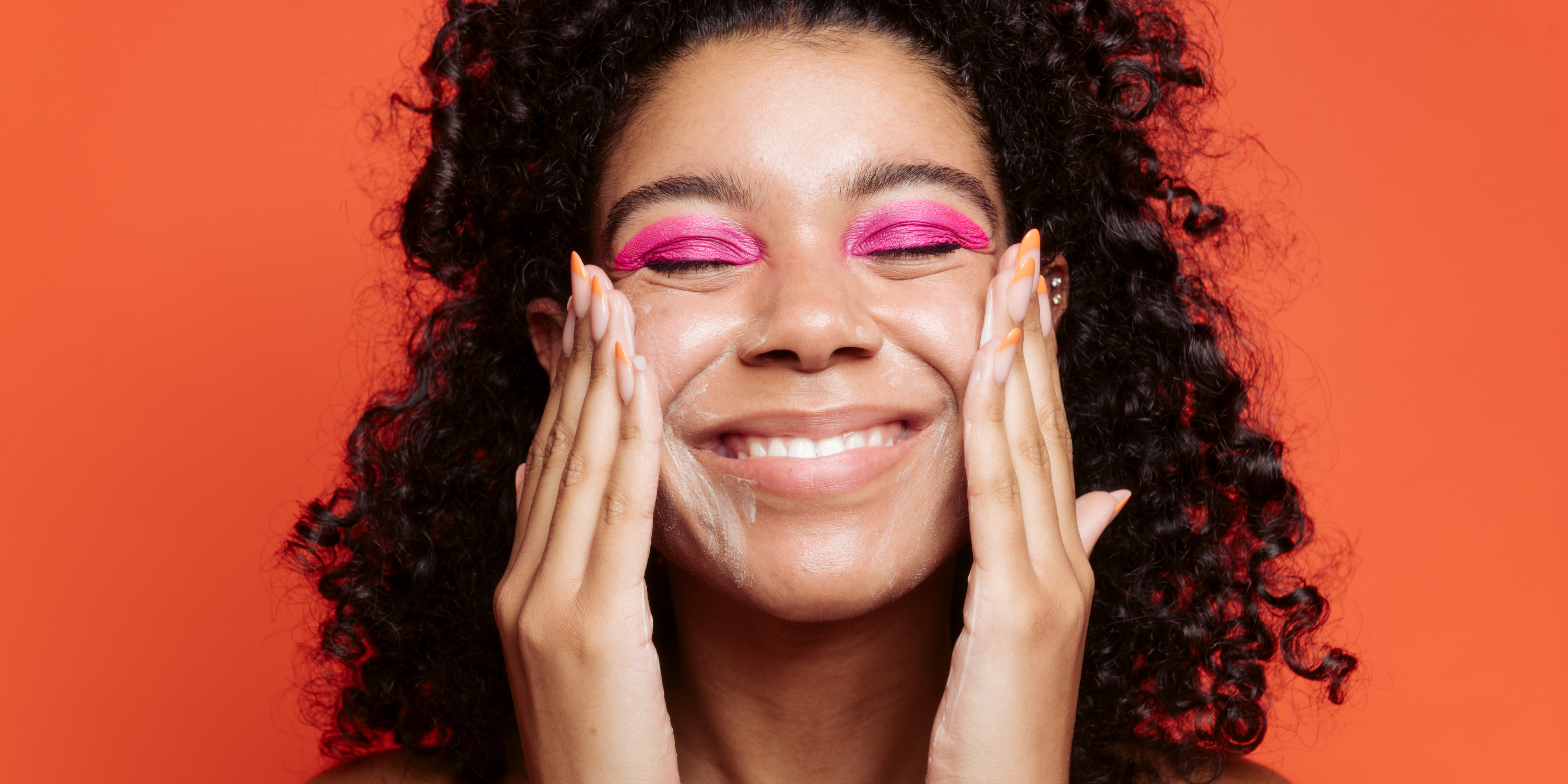 girl with brown curly hair, and pink eyeshadow washes her face with tbh anti-bacterial cleanser