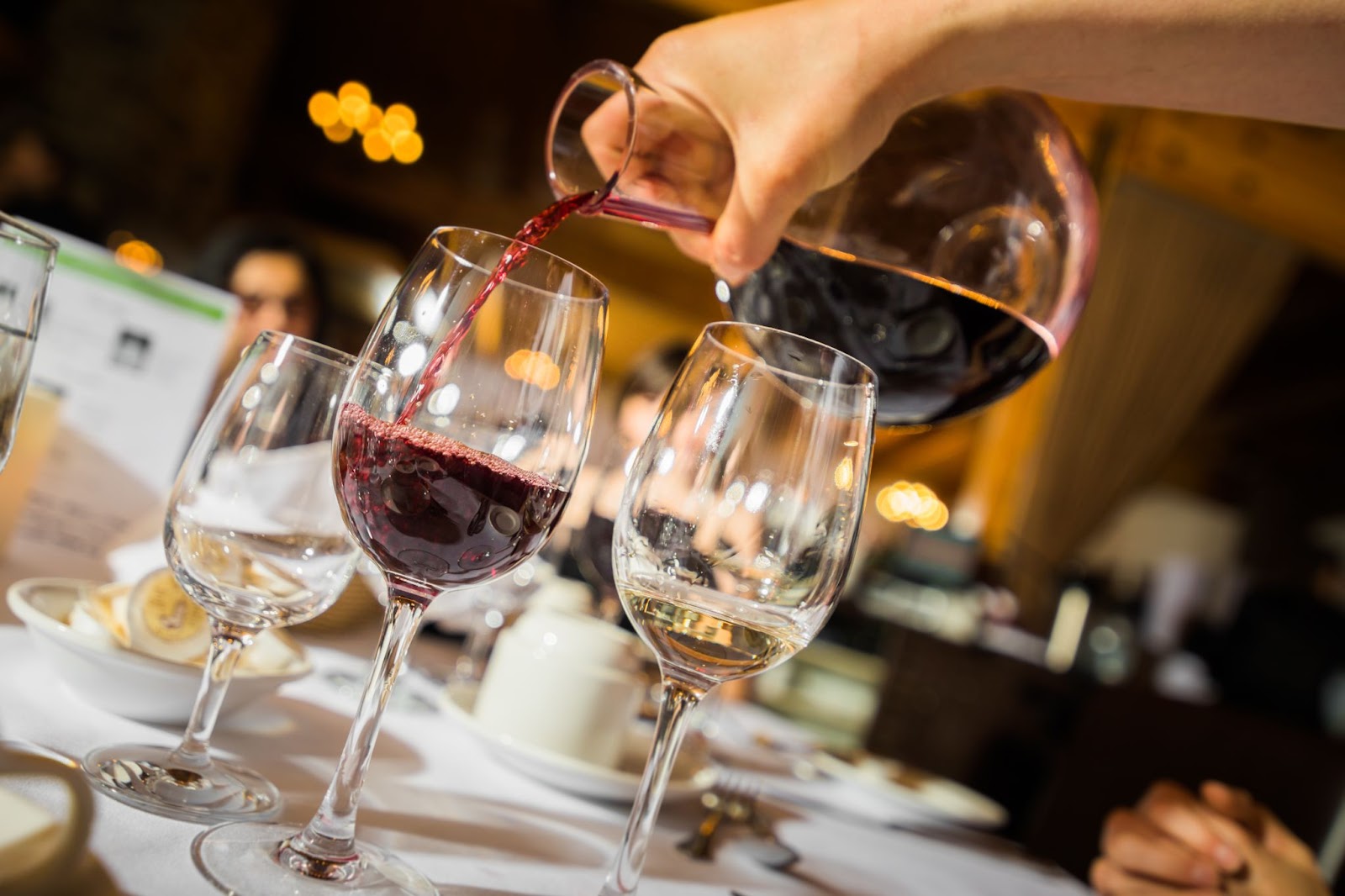 Hand pouring red wine to glass.