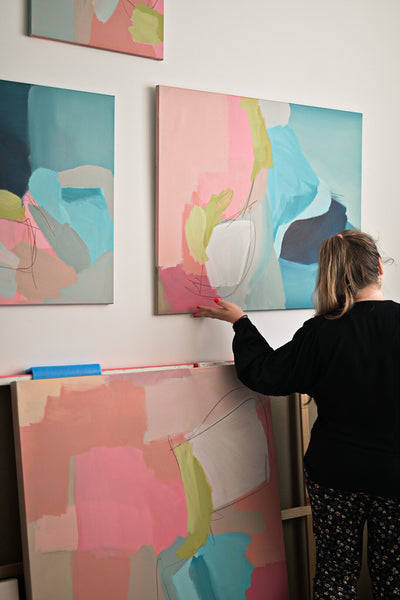 Dominika Montonen-Koivisto adjusting colorful abstract painting in her studio