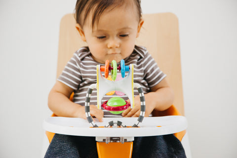 a baby in a high chair playing with  toy