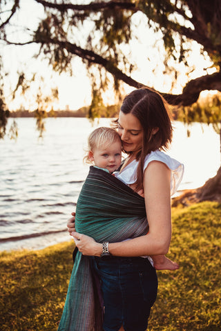 Young toddler worn by her mother in a Girasol "Always" ring sling by the river