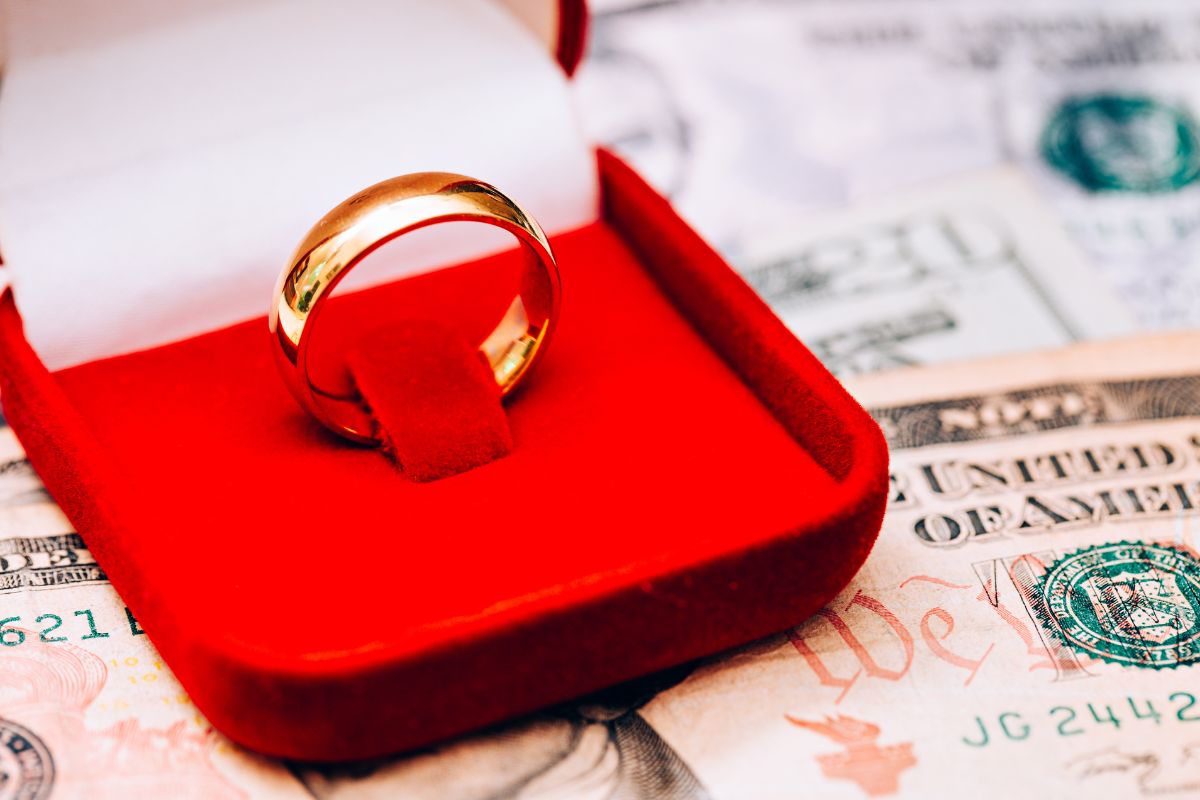 A beautiful engagement ring kept on some money depicting the cost it have.