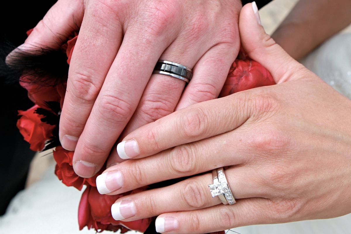 A guy and a girl wearing a wedding band and an engagement ring