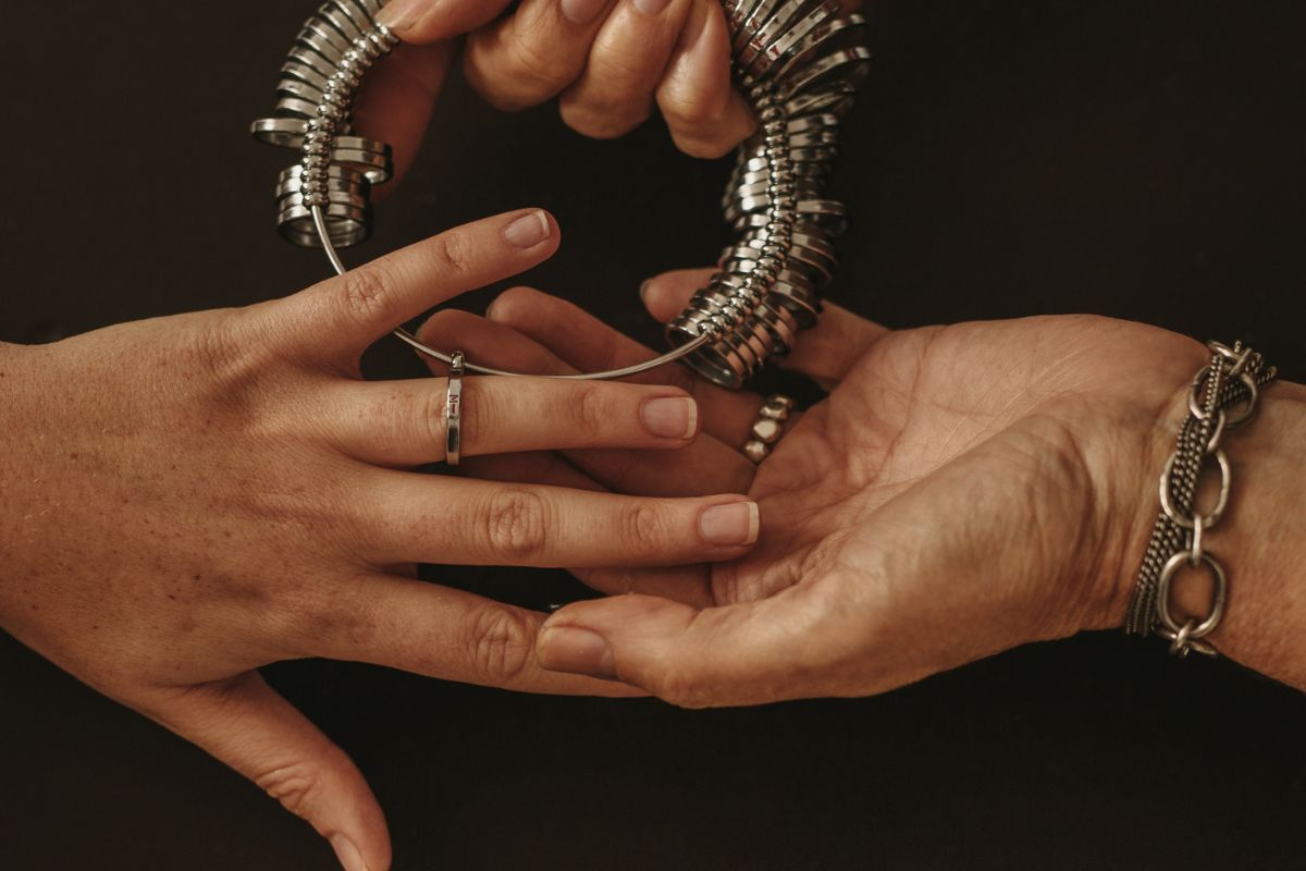 A guy measuring the custom ring size for a woman