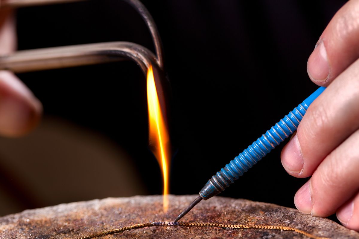 A jewelry craftsman soldering bail of necklace.