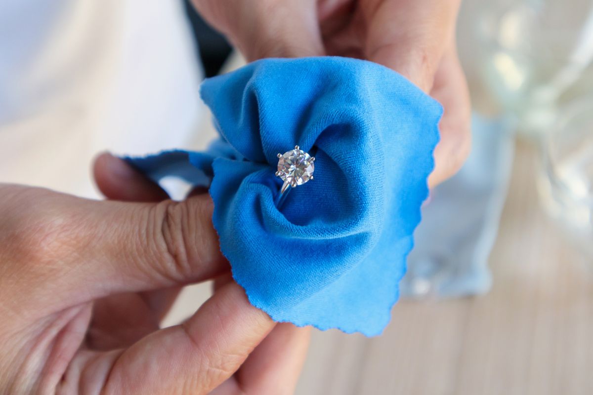 A lady cleaning her Round Brilliant cut diamond ring with soft fibre cloth.