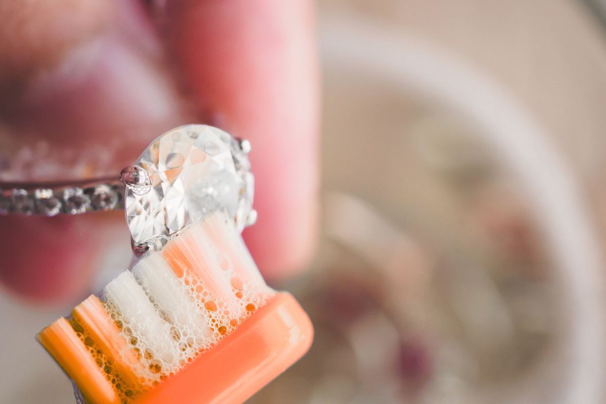 A lady cleaning her diamond ring with soft brush and mild soap