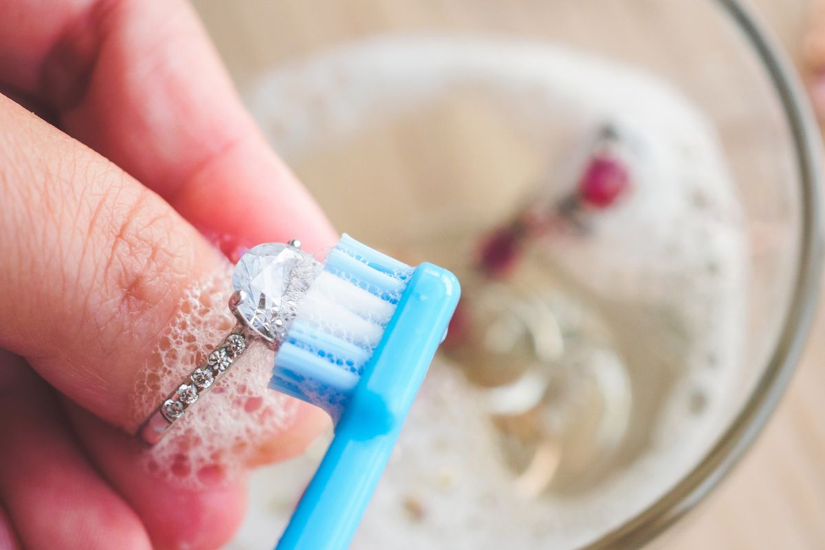 A lady cleaning her wedding ring with a toothbrush